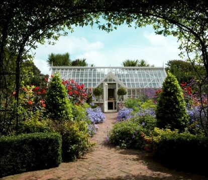 Freestanding greenhouse in beautiful flower garden