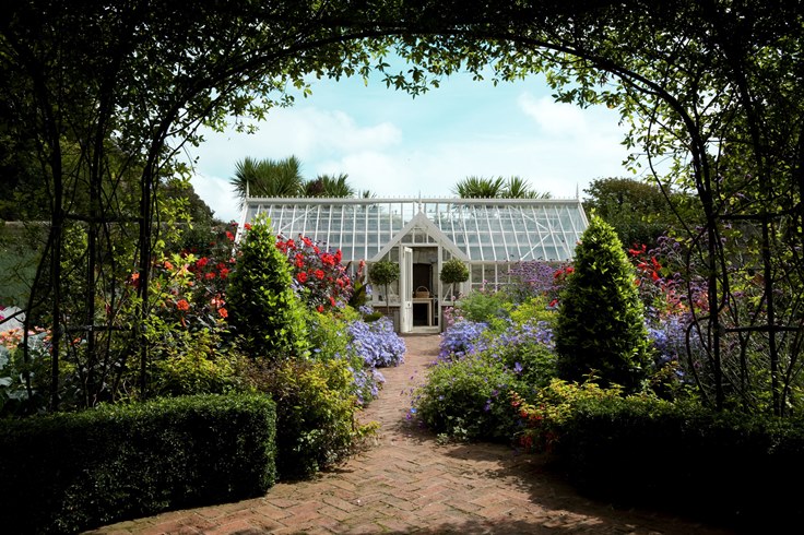 Freestanding greenhouse in beautiful flower garden