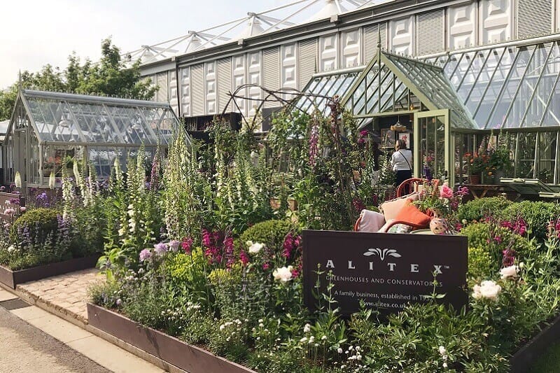 Colourful planting at Chelsea with Two Greehouses behind