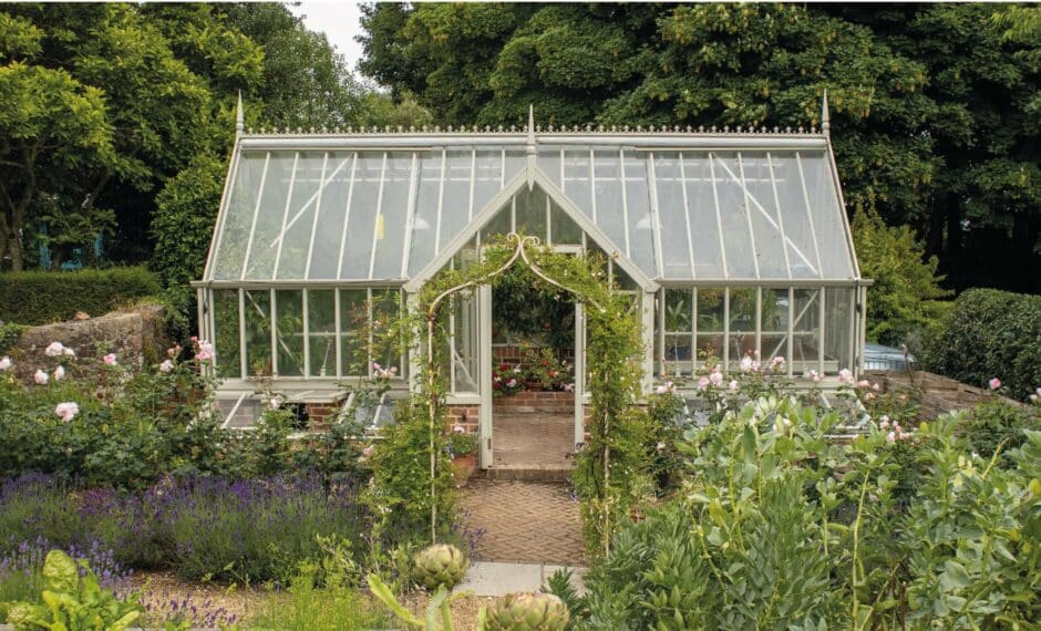 Victorian-style greenhouse with a front lobby in a vibrant garden