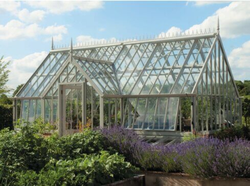 Alitex Cliveden Greenhouse in victorian style, with a front lobby and surrounded by plants and flowers