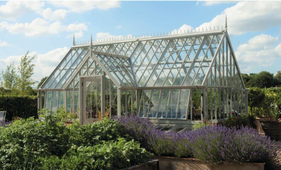 Alitex Cliveden Greenhouse in victorian style, with a front lobby and surrounded by plants and flowers