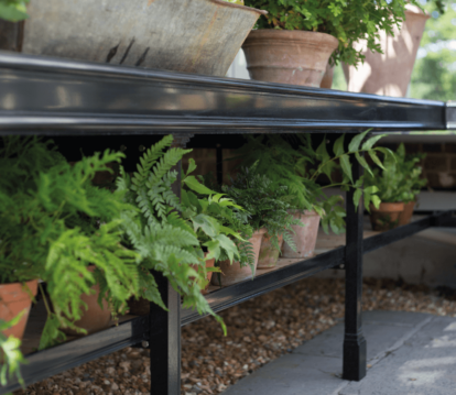 Close up of black Lower benching in greenhouse with potted plants on it