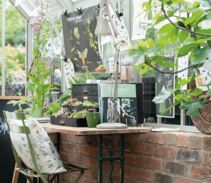 Internal shot of victorian greenhouse with a desk and chair against the side.