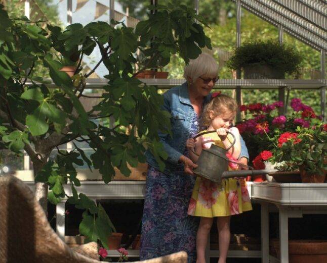 Grandma reading to child in greenhouse