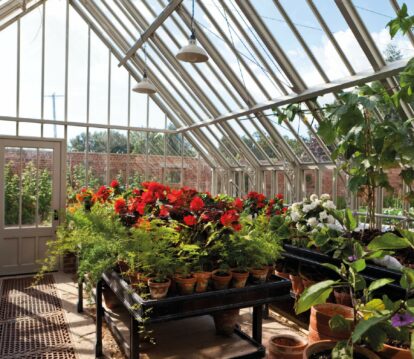 free standing benching inside greenhouse with potted flowers on top