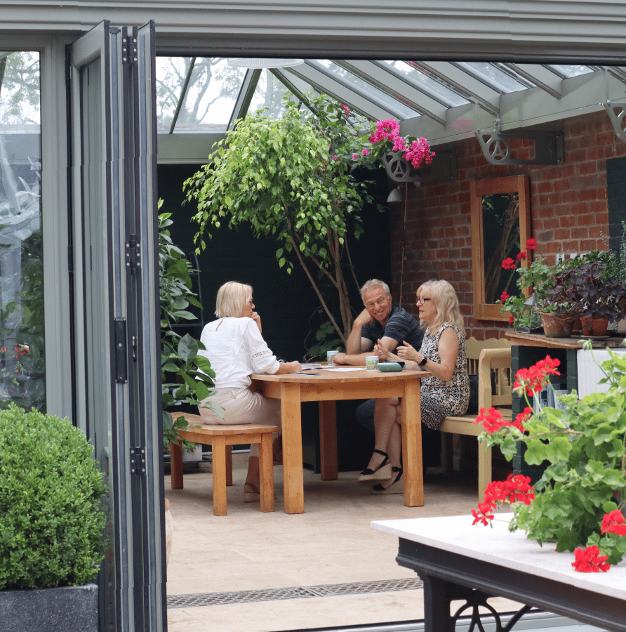 man and woman sat at wooden table inside conservatory talking to alitex sales designer