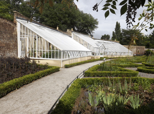 Large white lean-to greenhouse with central lobby in the walled gardens of Fulham Palace