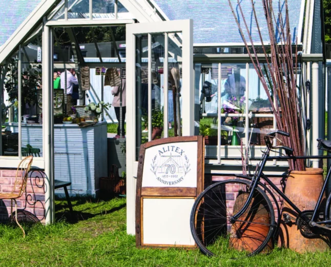 Alitex National Trust Mottisfont Greenhouse at Goodwood Revival, styled with an old vintage bike and car door at the front, with a large ceramic pot filled with sticks.