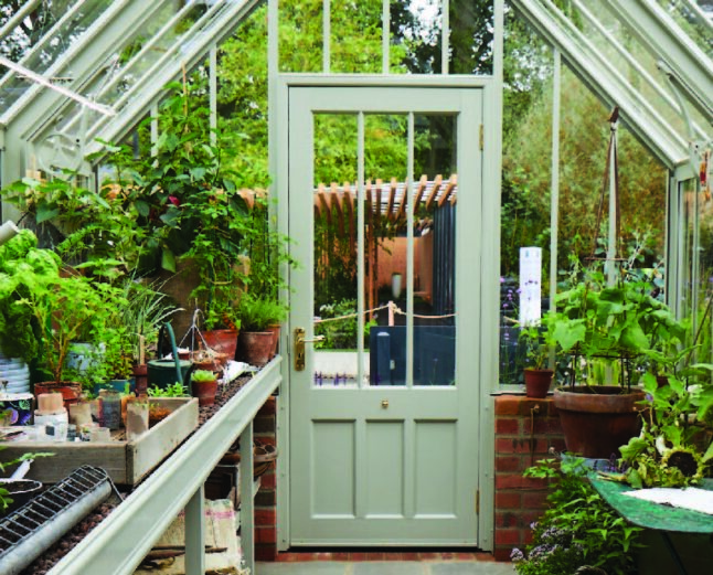Inside view of an Alitex Scotney greenhouse from their National Trust collection, filled with plants placed on the benching.