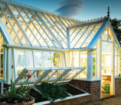 Eye-level view of greenhouse, lit up inside and dark outside as it's night time. Slight side profile of the greenhouse.